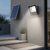 100W Solar LED Floodlight - Panel & Remote Kit mounted on a wall with a solar panel in the background.
