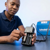 Man using a Double Battery Charger to charge batteries, showcasing its two-bay design and convenience.
