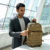 Man using Tactical Coyote Brown Rucksack at a modern workspace, showcasing its practical design and compartments.