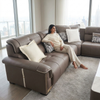 Woman relaxing on an L-Shaped Sectional Sofa in a modern living room with city view.