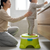 Toddler using a green Musical Toddler Potty Training Chair with adult assisting in a bathroom setting.