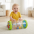 Smiling baby playing with Inflatable Baby Crawling Roller Toy with Rattle Balls on living room floor.
