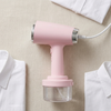 Handheld Garment Steamer with Large Capacity Water Tank next to white shirts on a beige fabric background.
