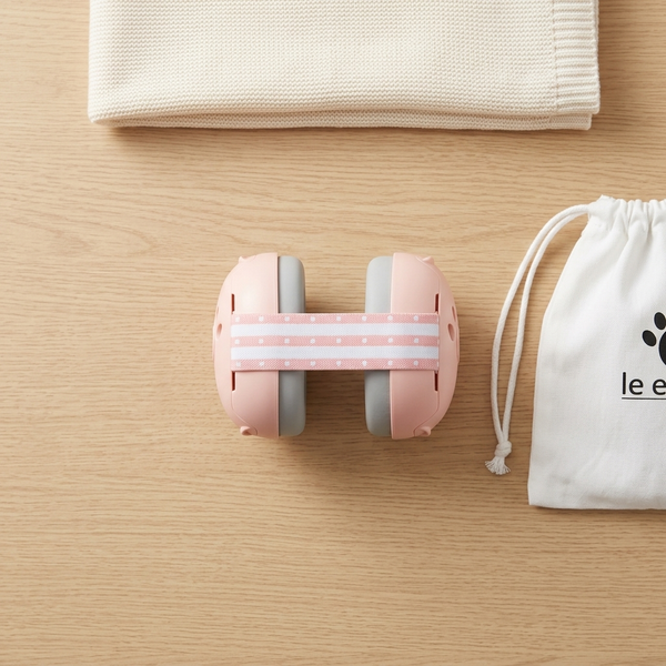 Baby Noise-Cancelling Hearing Protection Earmuffs in pink with soft padded ear cups on wooden surface.