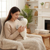 A person hugging a Plush Seal Soft Toy while sitting on a cozy couch with a warm drink.