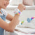 Girl wearing a colorful Slap Unicorn Bracelet while sitting at a desk with a notebook and a plush unicorn.