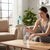 A young woman using a 2-Litre Motivational Water Bottle with Built-In Straw at home to stay hydrated.