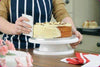 Person using a Rotating Cake Turntable Decorating Stand to smooth icing on a cake.