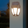 Solar Motion-Activated Wall Lamp illuminating a garden wall at night with solar panels on top.