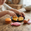 Child playing with Colorful Plastic Pretend Food Play Set, including pizza, burger, fish, and chicken on a wooden table.