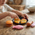 Child playing with Colorful Plastic Pretend Food Play Set, including pizza, burger, fish, and chicken on a wooden table.