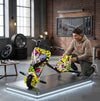 A young man assembling a colorful 36V 3-Wheel Electric Drifting Trike in a modern garage setting.