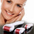 A smiling woman showcasing the 4 in 1 Derma Roller Cosmetic Kit with three rollers for skincare.