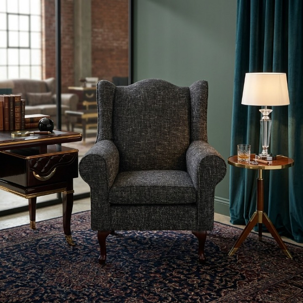 Serena Grey Fabric Wingback Chair in a stylish living room setting with a lamp and side table.
