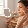 Woman using a Portable Square LED Makeup Mirror to apply blush while getting ready.