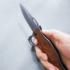 Tactical Trench Folding Knife held in hand showcasing its sharp blade and secure knuckle guard.