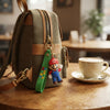 3D Plumber Silicone Keychain attached to a stylish backpack near a cup of coffee.