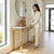 A woman placing a handbag on a Luxury Faux Marble Gold Base Console Table in a modern foyer.