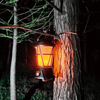 Outdoor Flicker LED Lantern hanging on a tree, casting warm light in a nighttime forest setting.