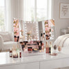 360-Degree Rotating TriFold Makeup Mirror with LED & Storage arranged on a vanity with cosmetics and beauty tools.