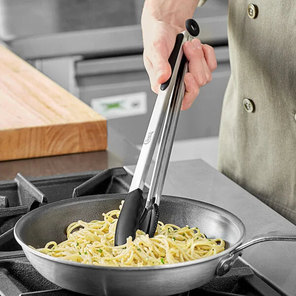 Durable Stainless Steel and Silicone Kitchen Tong mixing pasta in a skillet on a kitchen stove.