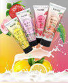 Four tubes of Body Milk Body Lotion by Karité, featuring fruit scents, with splash of citrus in the background.