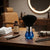 Blue and Black Barber Neck Duster Brush sitting on a barber's table beside grooming tools and Bay Rum.