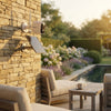 4G Solar-Powered Outdoor Security Camera mounted on a stone wall with a solar panel, providing surveillance in a garden.