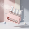 4-in-1 Acrylic Travel Refillable Bottles Set 50ml displayed in a pink holder with spray pumps, surrounded by bubbles.