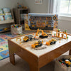 Construction Vehicle Playset on a table with toy construction vehicles and accessories in a playroom setting.