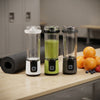 Digital Display Portable Juicer in three colors with smoothies, oranges, and a yoga mat on a table.
