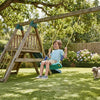 A child happily playing on an Outdoor Home Swing for Kids in a backyard with greenery and flowers.