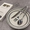 Stainless Steel Cutlery Set displayed on a plate with a box, featuring a knife, fork, and spoon in a sleek design.