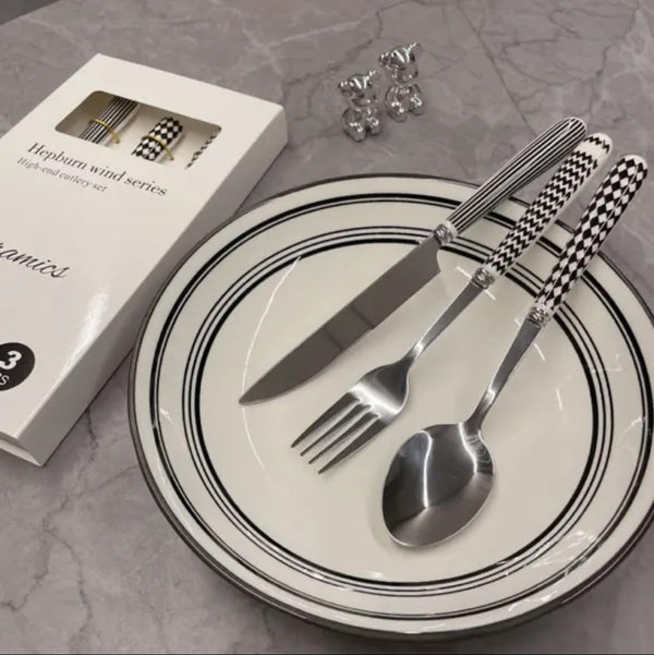 Stainless Steel Cutlery Set displayed on a plate with a box, featuring a knife, fork, and spoon in a sleek design.