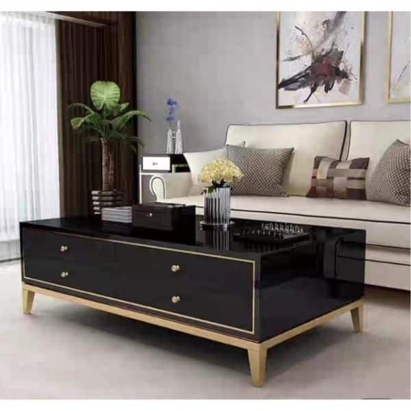 Four Drawer Coffee Table with a sleek black finish and gold accents, placed in a modern living room setting.