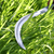 Wooden Handle Harvesting Sickle cutting through tall grass, showcasing its sharp curved blade for efficient harvesting.