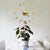 3D DIY Mirror Golden Surface Wall Clock Roman Numeral above a potted plant on a dining table.