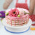 Rotating Cake Turntable Decorating Stand with a beautifully decorated pink cake topped with flowers.
