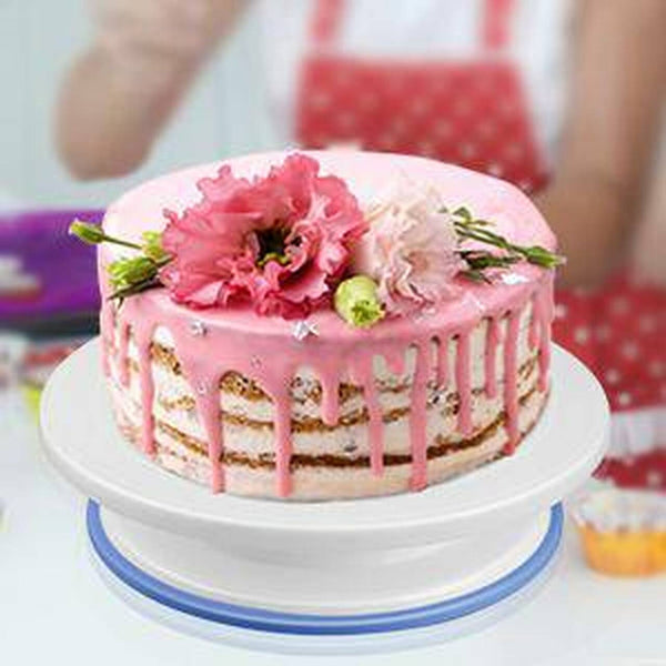 Rotating Cake Turntable Decorating Stand with a beautifully decorated pink cake topped with flowers.