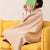 A person wearing a Portable Wearable Electric Heated Shawl Blanket while reading on a yellow couch.