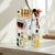 360 Rotating Cosmetic Organizer displaying various beauty products and makeup brushes on a stylish vanity.