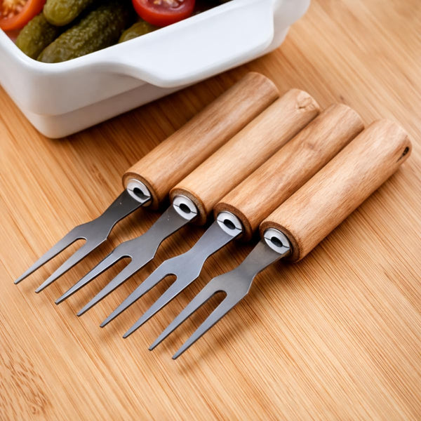 Set of 6 Stainless Steel Fruit Forks with Wooden Handles arranged on a wooden surface beside a bowl of snacks.