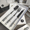 Stainless Steel Cutlery Set displayed in a box featuring a spoon, fork, and knife with stylish black and white handles.