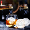 Pouring drink into a glass with Sports Ice Ball Molds in football and basketball shapes beside it.