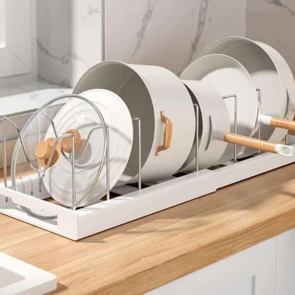 Adjustable Pots and Pans Organizer displaying white pots on a countertop with a wooden finish in a bright kitchen setting.