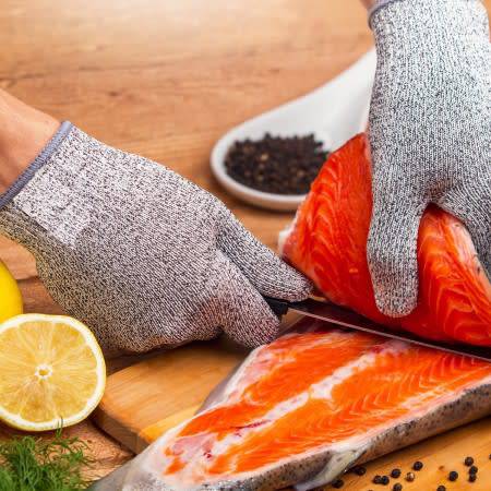 Person using Safety Kitchen Cut Resistant Gloves while cutting salmon fillet on a wooden cutting board.