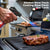 Windproof Portable Cartridge Gas Torch Lighter in use, igniting food on a grill in a kitchen setting.