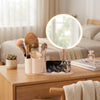 LED Makeup Mirror with Rotating Cosmetic Organizer on a wooden vanity with makeup brushes and phone stand.