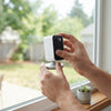 A person installing the 3MP 2K Wireless Window Security Camera on a window for indoor-to-outdoor surveillance.