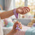A child holding a 3D Rainbow Unicorn Keychain with a purple wrist strap in a bright room.